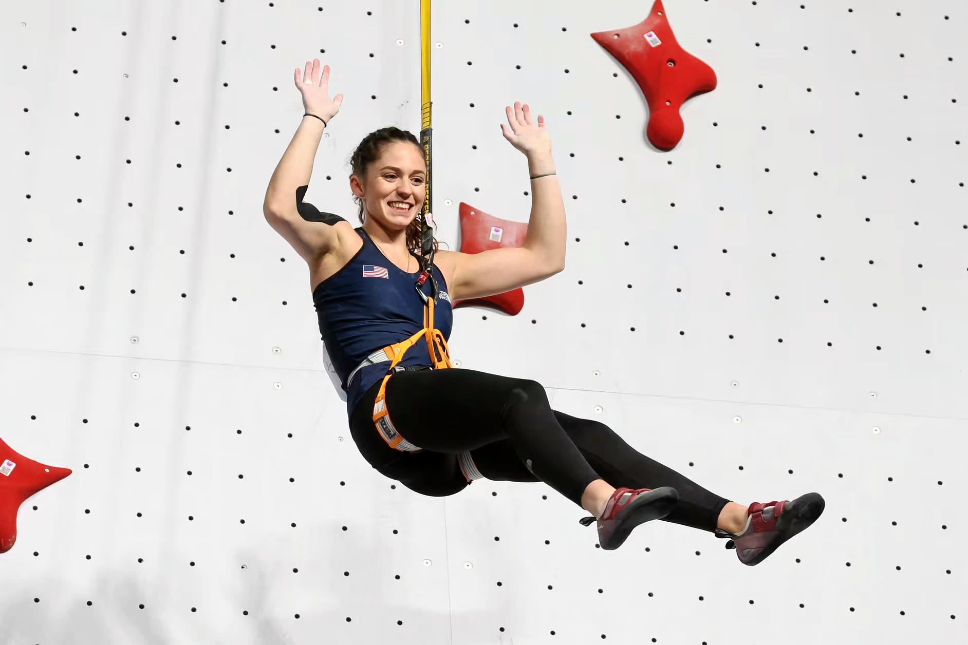 Piper Kelly waving from the climbing wall after she qualified for Paris Olympics.