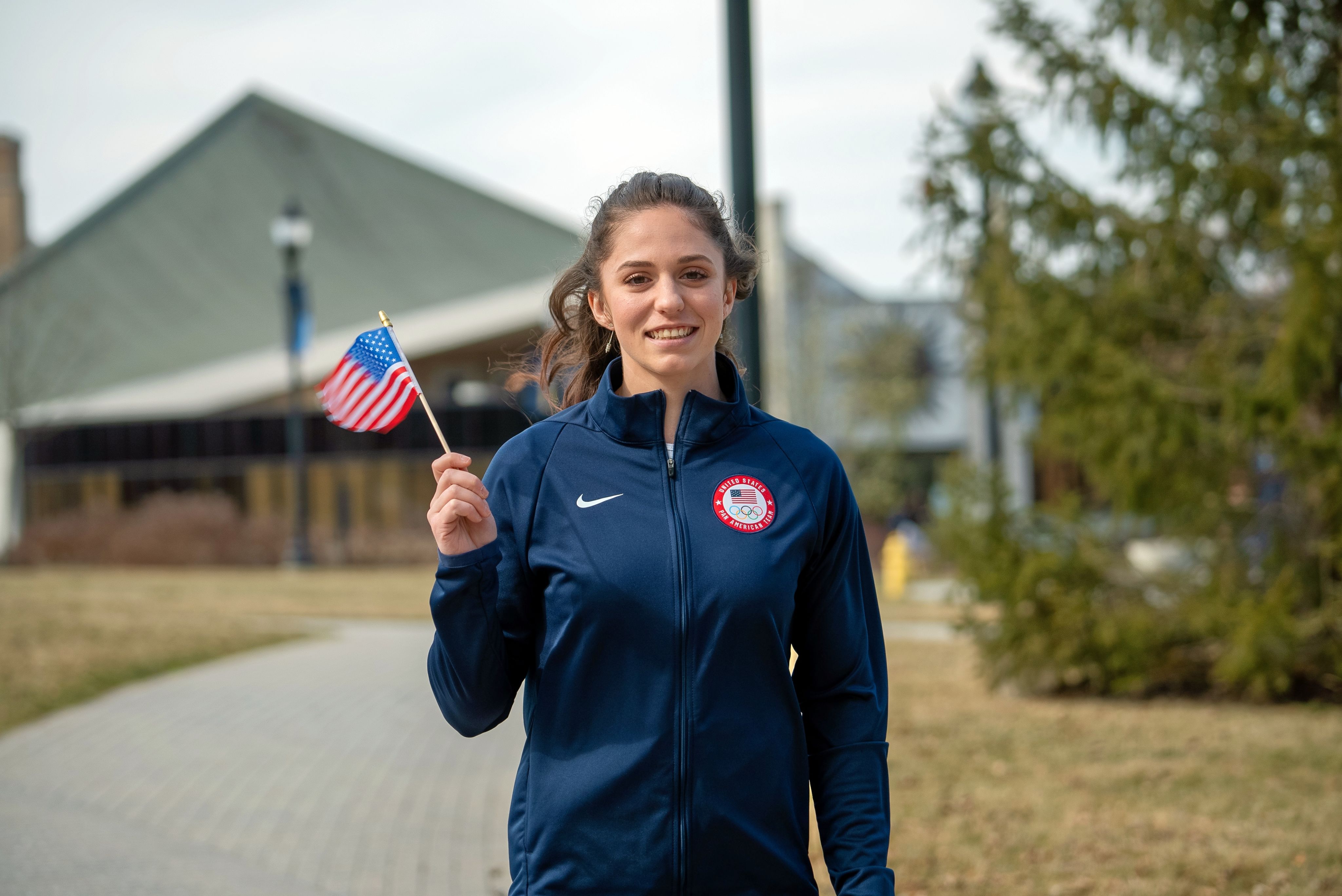 Piper Kelly, speed climber holding an American flag on Xavier's campus.